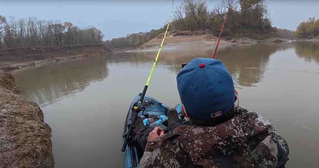Spencer Bauer fishes from his kayak near a steep muddy bank, preparing to battle winter catfish on a cold, overcast day.