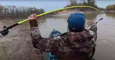 Spencer Bauer’s bright-green Hellcat rod bends sharply as he reels in a feisty winter catfish from his kayak.
